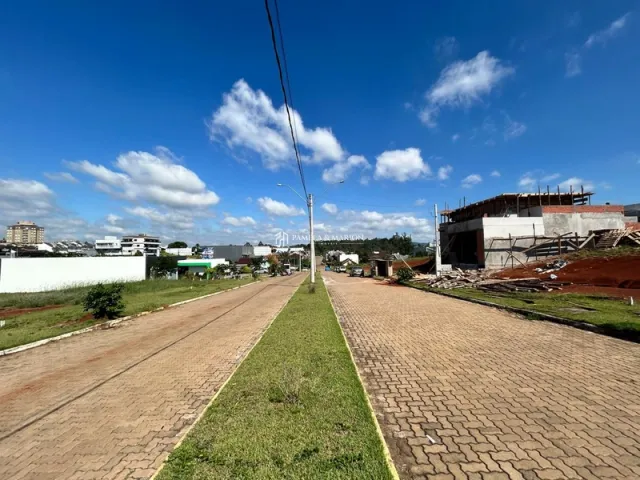 Vista de uma rua pavimentada com gramado e área de construção ao fundo.