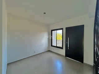 Foto de uma sala interna com paredes brancas e piso claro.
