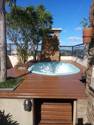 Foto de uma área externa com jacuzzi em um terraço de madeira.