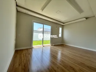 Sala de estar com piso de madeira e porta de vidro que dá acesso ao jardim.