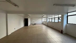 Vista interna de um corredor com piso de cerâmica e grandes janelas.