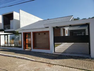 Fachada externa de uma residência branca em Lajeado, Brasil, com detalhes em painéis escuros.