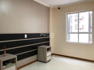 Foto de um ambiente interno com parede de estantes escuras e janela.