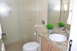 Foto de um banheiro interno com azulejos claros e louças sanitárias.