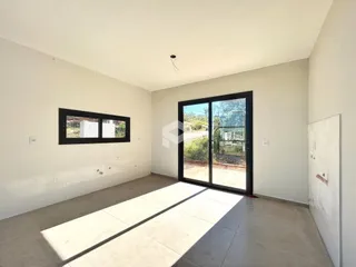 Ambiente interno de uma sala ampla com piso de cerâmica e grandes portas de vidro.
