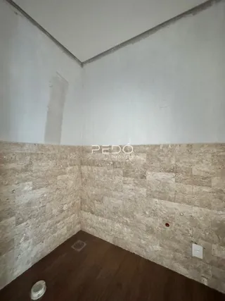 Interior de um cômodo com paredes de alvenaria e piso de madeira.