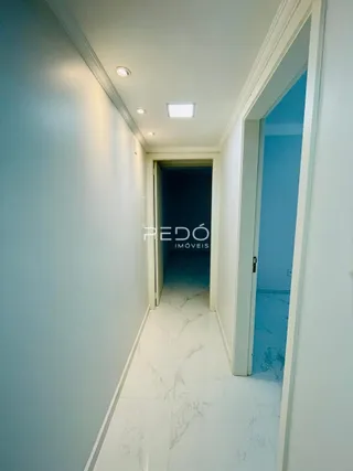 Corredor interno com piso de mármore branco em uma residência.
