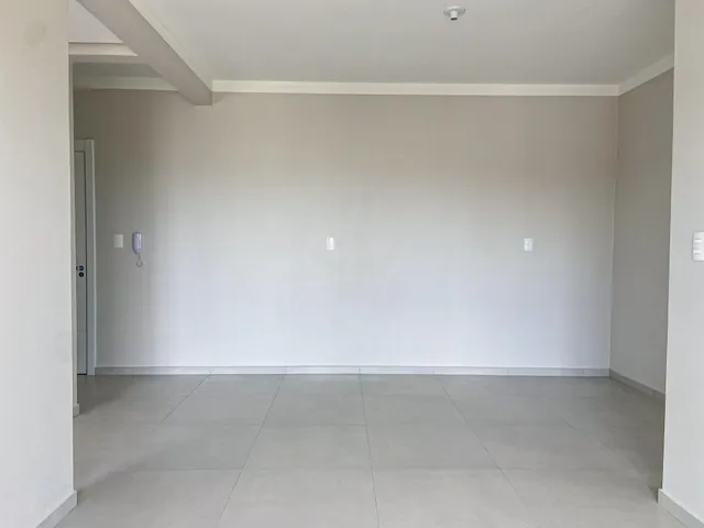 Hall de entrada com paredes brancas e piso de cerâmica.