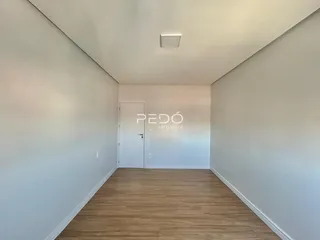 Um corredor interno com piso de madeira clara e paredes brancas.