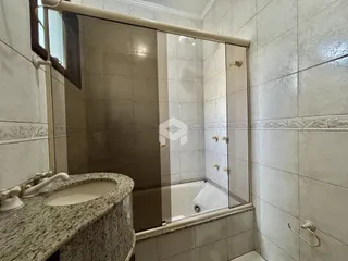 Banheiro com box de vidro e pia de granito.