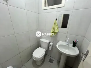 Banheiro com revestimento de azulejos brancos e pia branca.