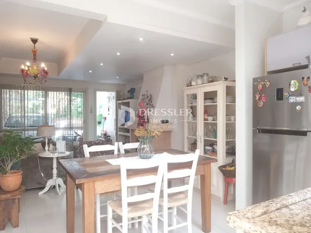 Sala de jantar com mesa de madeira e estantes brancas em um imóvel no Brasil.