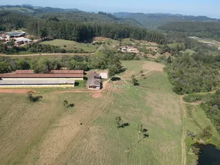Vista aérea de uma propriedade rural com campos e vegetação ao redor.