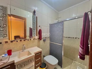 Banheiro com revestimento de cerâmica e box de vidro.