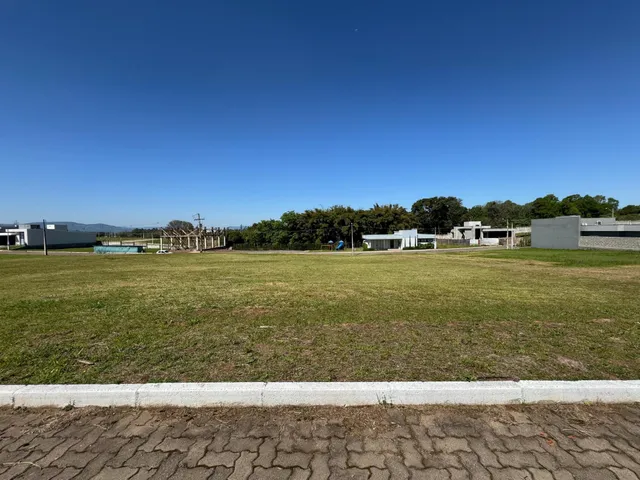 Vista externa de um terreno gramado com estruturas ao fundo.