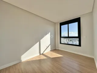 Sala de estar com piso de madeira e grande janela com vista para a cidade.
