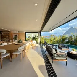 Área comum interna com vista para uma piscina e paisagem.