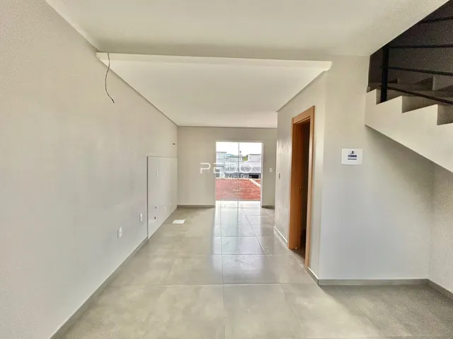 Corredor interno de uma residência com paredes brancas e piso de cerâmica.