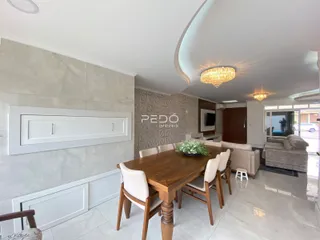 Vista da sala de jantar com mesa de madeira e cadeiras em um imóvel no Brasil.