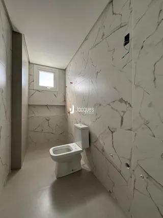 Corredor interno com revestimento de mármore nas paredes e vaso sanitário branco.