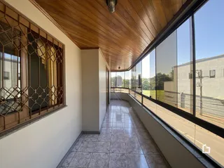 Vista de um corredor interno com teto de madeira e grandes janelas de vidro.
