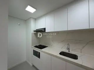 Cozinha moderna com armários brancos e bancada clara.
