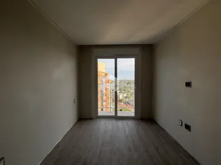 Interior de um ambiente com piso de madeira e porta de vidro que dá para a vista.