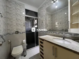 Banheiro com revestimento de azulejos e bancada de granito.