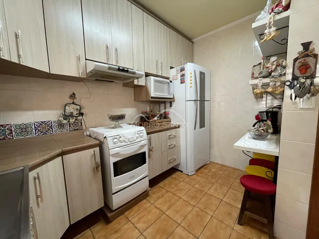 Cozinha com armários de madeira e revestimento de azulejos brancos.