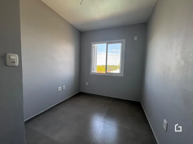 Interior de um cômodo com paredes cinzas e piso de concreto.