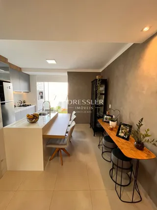 Vista de uma sala de jantar moderna com mesa de madeira clara e armários brancos.