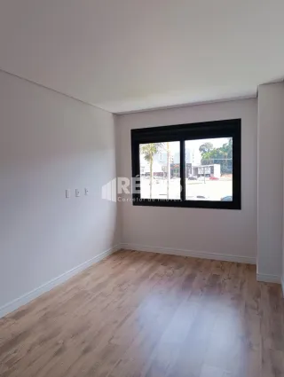 Ambiente interno de uma sala com piso de madeira clara e paredes brancas.