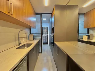 Cozinha moderna com armários de madeira e bancadas claras.