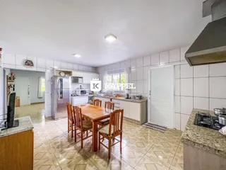 Foto de uma cozinha com mesa de jantar de madeira e armários brancos.