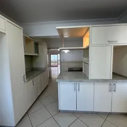 Cozinha com armários brancos e piso de cerâmica.