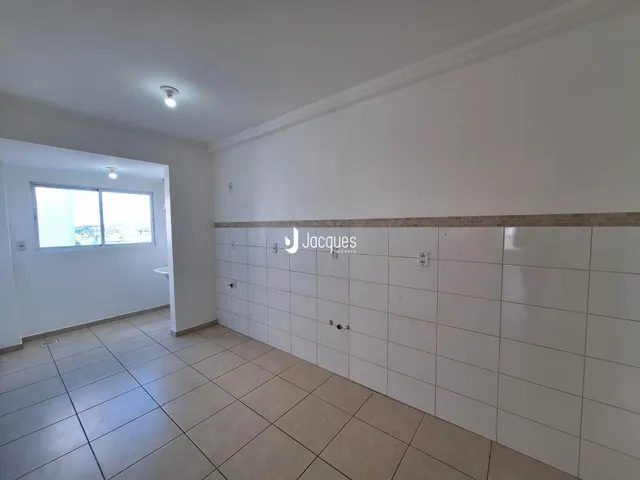 Hall de entrada com piso de cerâmica clara e paredes brancas.