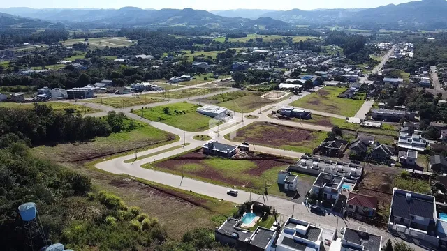 Vista aérea de uma área residencial com campos e vegetação no Brasil.