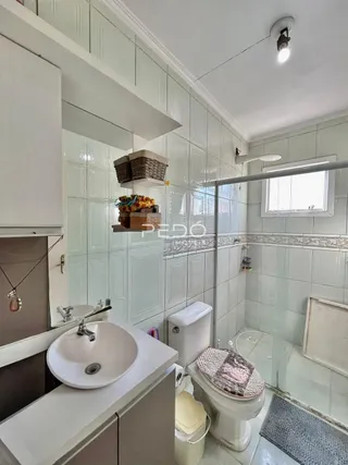A foto mostra o interior de um banheiro com revestimento de azulejos brancos.
