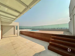 Vista de uma área externa com deck de madeira e piscina.