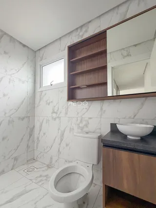 Foto de um banheiro com revestimento de mármore branco e louças modernas.