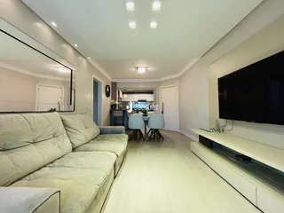Sala de estar com sofá grande e televisão na parede.