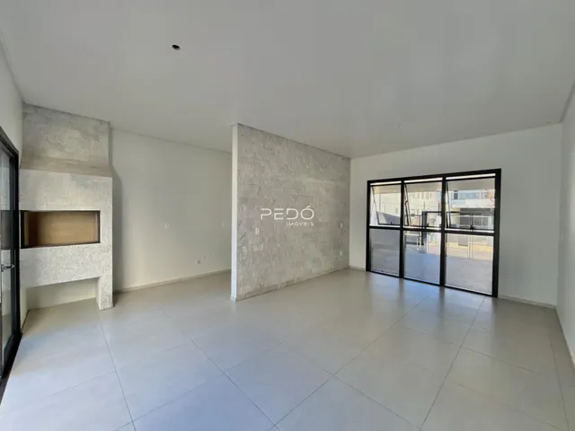 Sala de estar ampla com piso claro e paredes brancas em um imóvel.