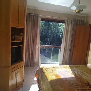 Quarto com armários de madeira e vista para a vegetação externa.