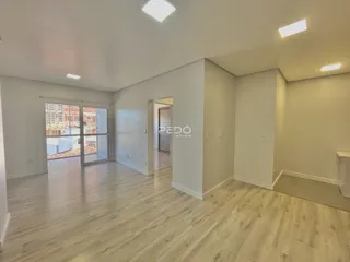 Sala de estar com piso de madeira clara e porta de vidro que dá para o exterior.
