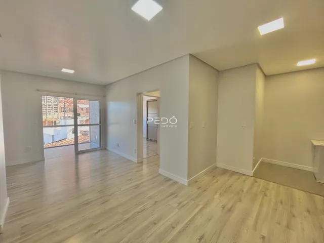 Sala de estar com piso de madeira clara e porta de vidro que dá para o exterior.