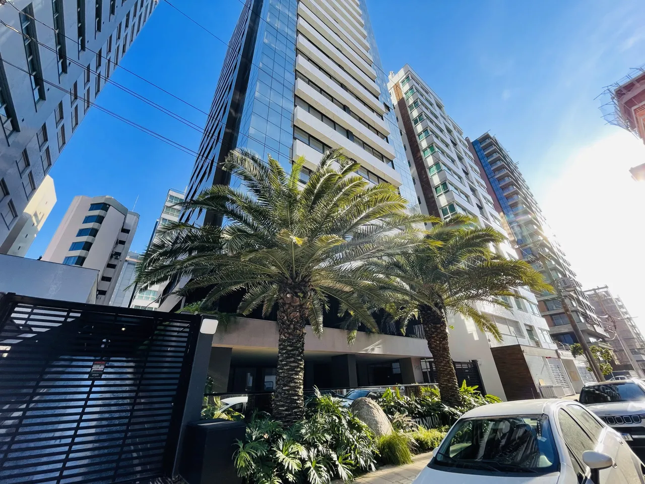 Vista externa de edifícios residenciais em Lajeado, Brasil, com palmeiras em primeiro plano.