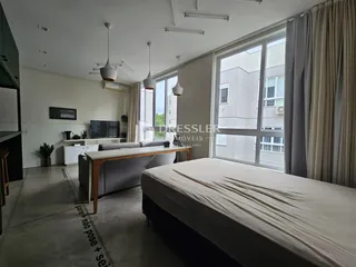 Ambiente interno de uma sala de estar com grande janela e cortinas.