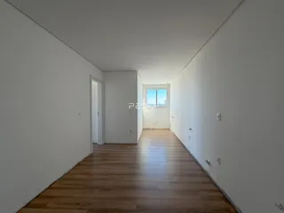 Corredor interno de uma residência com piso de madeira clara.