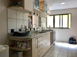 Cozinha com armários brancos e bancada clara em um imóvel no Brasil.