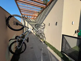 Vista lateral de uma parede externa com bicicletas estacionadas em uma área pavimentada.